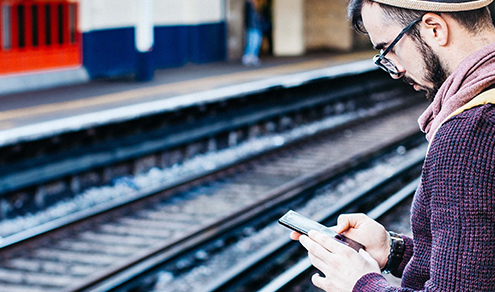 Tourist waiting on train platform looking at his mobile phone